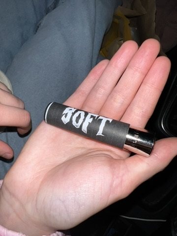 Hand holding a lighter printed with the word SOFT in gothic lettering